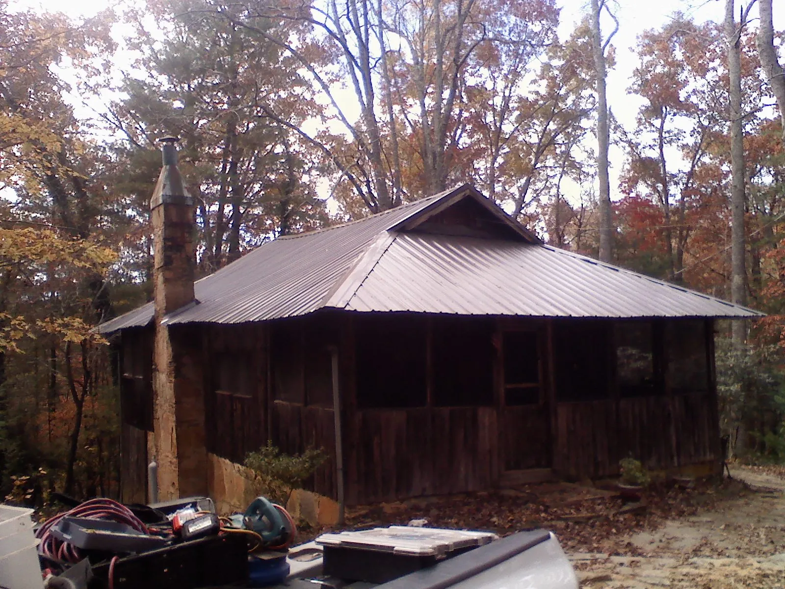 Brown metal hip roof on an old cabin with a stone chimney in Mount Pleasant