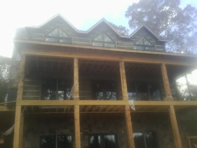 Dormers and porch framing on a large log home under construction — Roof Coating work by our crew in Mount Pleasant